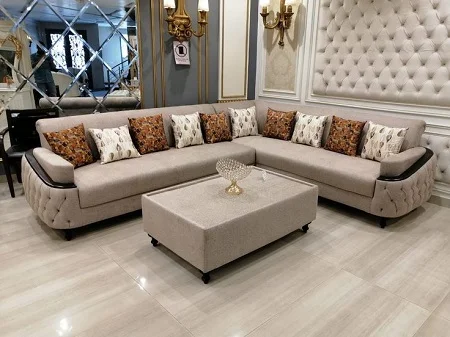 Beige tufted L-shaped corner sofa with patterned pillows