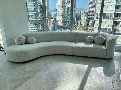 Curved gray boucle sofa with round bolster pillows