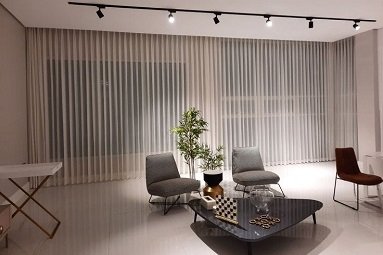 Floor-to-ceiling sheer curtains in modern living room with track lighting