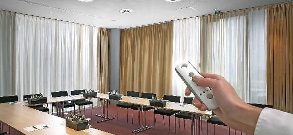 Hand operating remote-controlled motorized curtains in meeting room