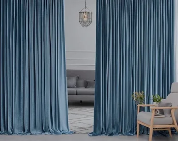 Blue velvet floor-length curtains framing a gray sofa and armchair in modern living room