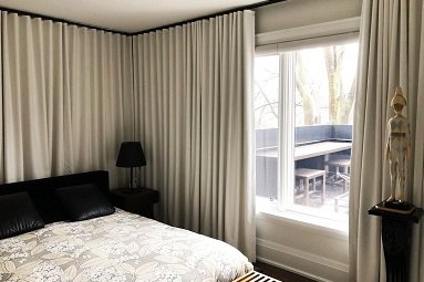 Cream floor-length curtains framing bedroom window with floral bedding