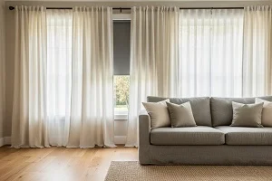 Cream linen curtains over sheers with gray sofa in bright living room