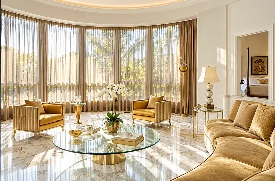 Floor-to-ceiling sheer curtains on curved windows in luxury gold and marble living room